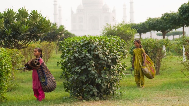 Girls work in the Mehtab Bagh (Moonlight Garden) in sight of the famous Taj Mahal palace.