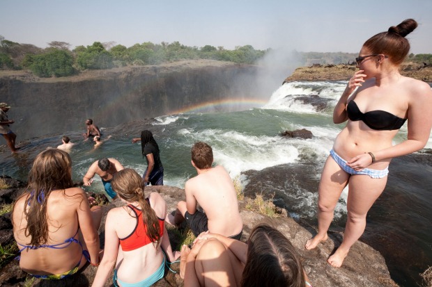 Tourists swimming in Devils Pool at the edge of Victoria Falls.