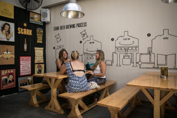 Three tourist chat in Stark Beer house on Legian Street in Kuta, Bali, Indonesia.