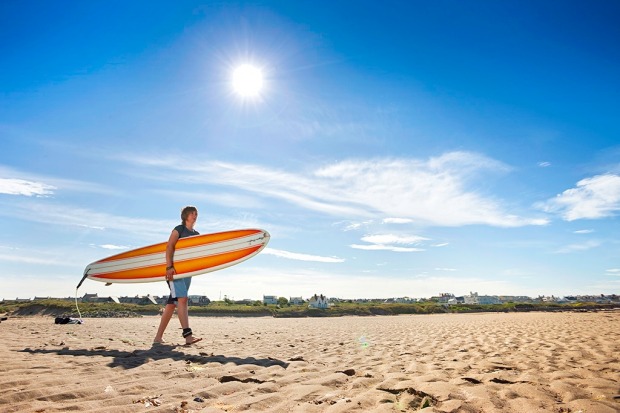 Surfer on the beach at Rhosneigr in Anglesey, North Wales.