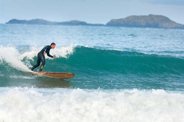 Surfer riding waves near St David's, Pembrokeshire, Wales.