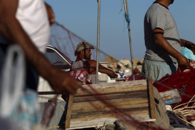 Fishermen comb their nets in the small coastal village of Palamut, Turkey.