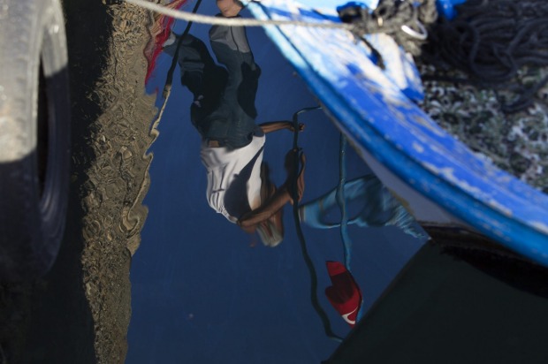 Water reflections of a fishermen at work in the small village of Palamut, Turkey.