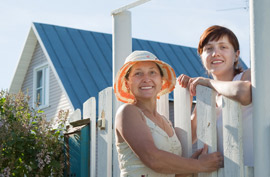 two women in front of a gate in front of a house