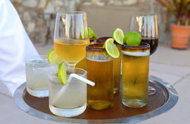 waiter's arm holding round tray holding a selection of alcoholic drinks