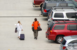 couple walking through a parking lot pulling a suitcase