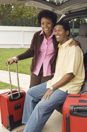 couple with suitcases leaning inside car hatchback