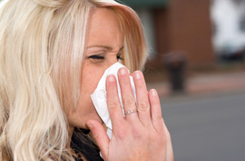 blonde woman blowing her nose