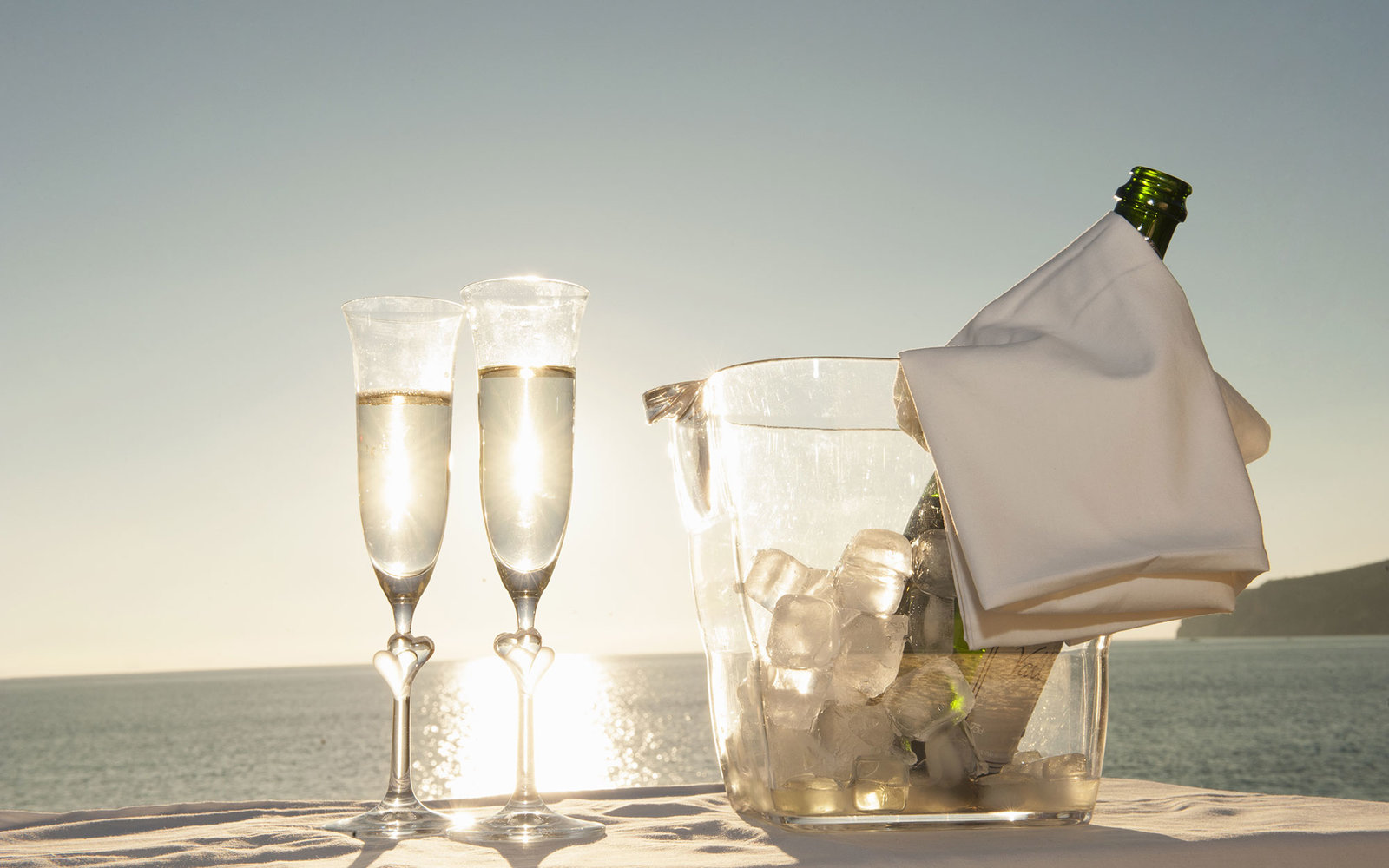 Champagne flutes and bucket against sunset